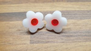 White daisy studs with live red centres